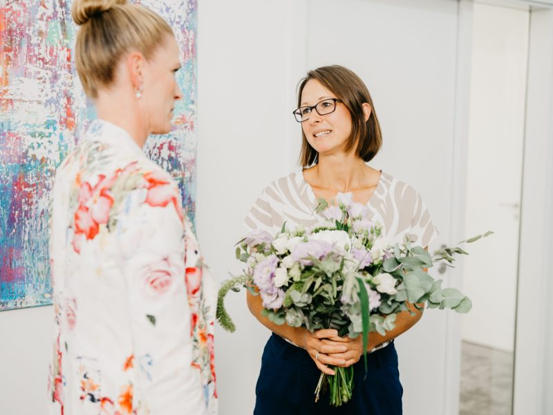 Mitarbeiterin bei QUATTEK & PARTNER erhält Blumen – wertschätzende Unternehmenskultur